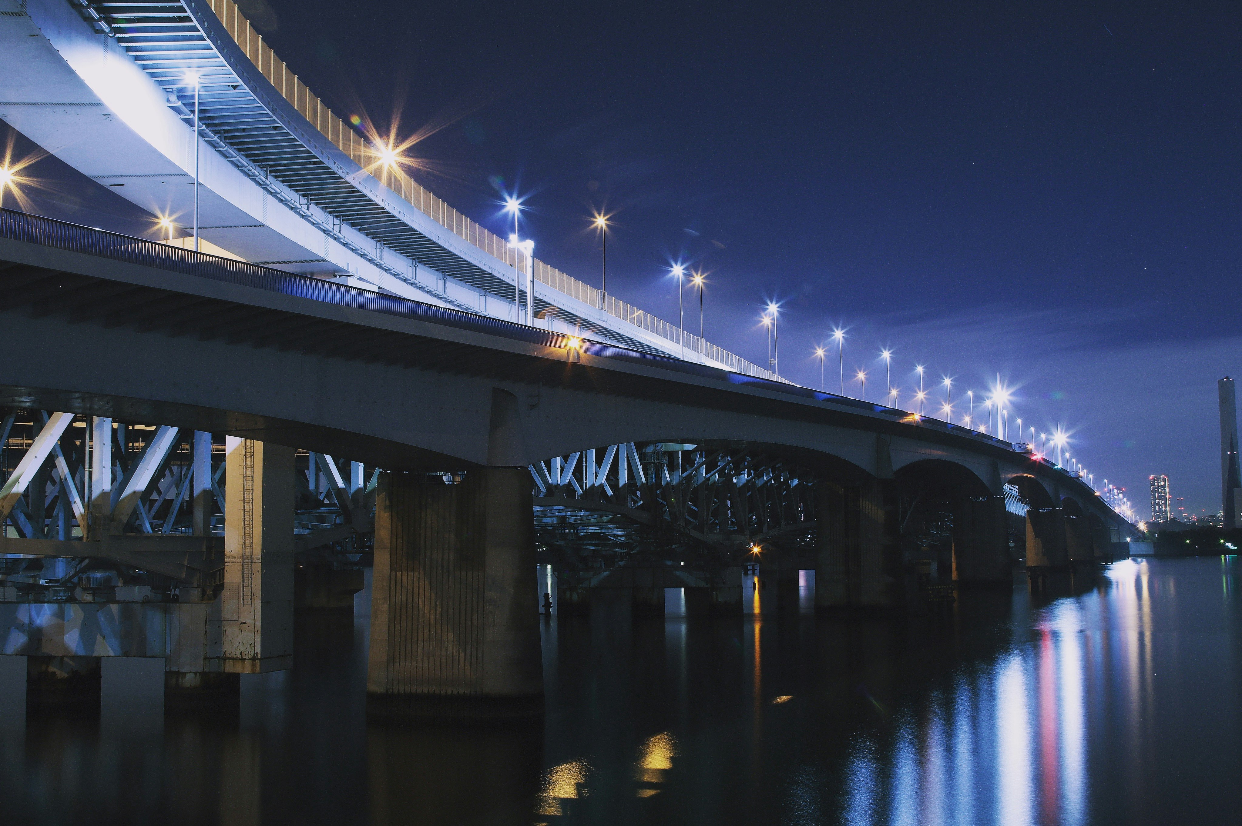 lighted bridge above calm body of water at night